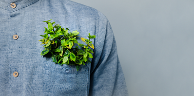 Fair Fashion setzt auf nachhaltig produzierte Mode. Es ist ein Hemd mit einer Grünpflanze in der Brusttasche zu sehen.