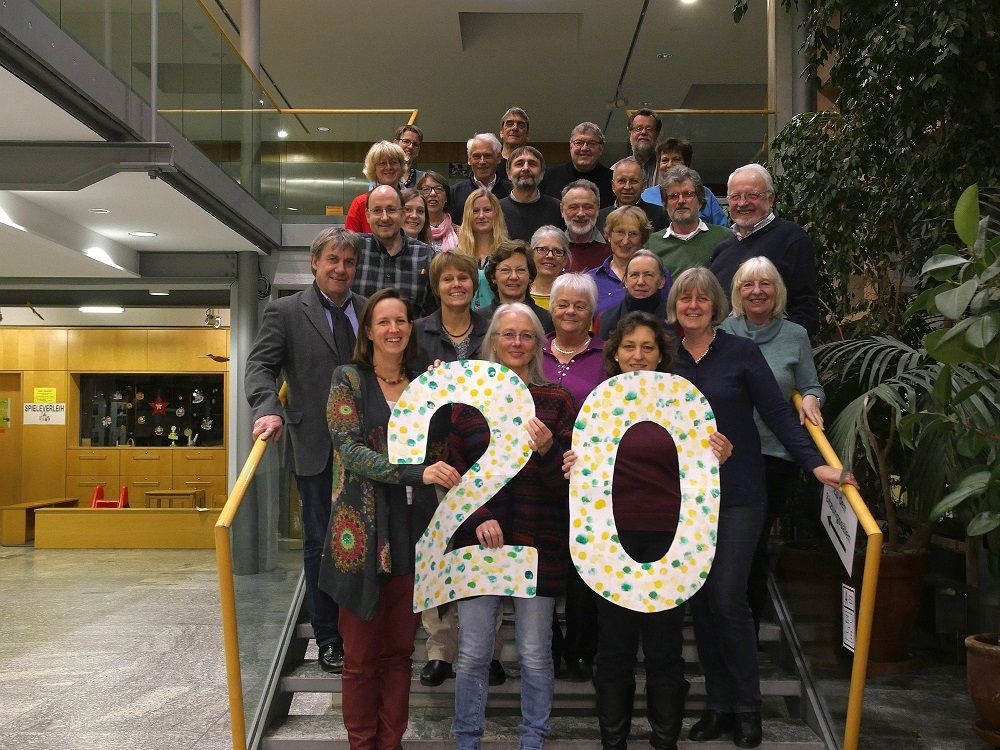 Beteiligte der Agenda 21 im Landkreis Fürstenfeldbruck stehen auf einer Treppe und halten in großen Lettern die Zahl 20 hoch zur Feier des 20-jährigen Jubiläums.
