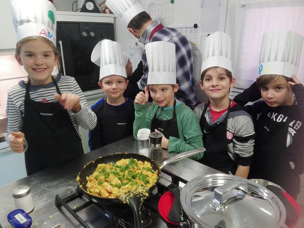 Kinder präsentieren stolz und glücklich ihr selbstgekochtes Essen.