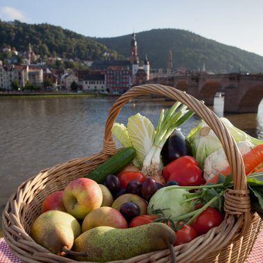 Korb gefüllt mit Obst und Gemüse vor der Stadtkulisse von Heidelberg