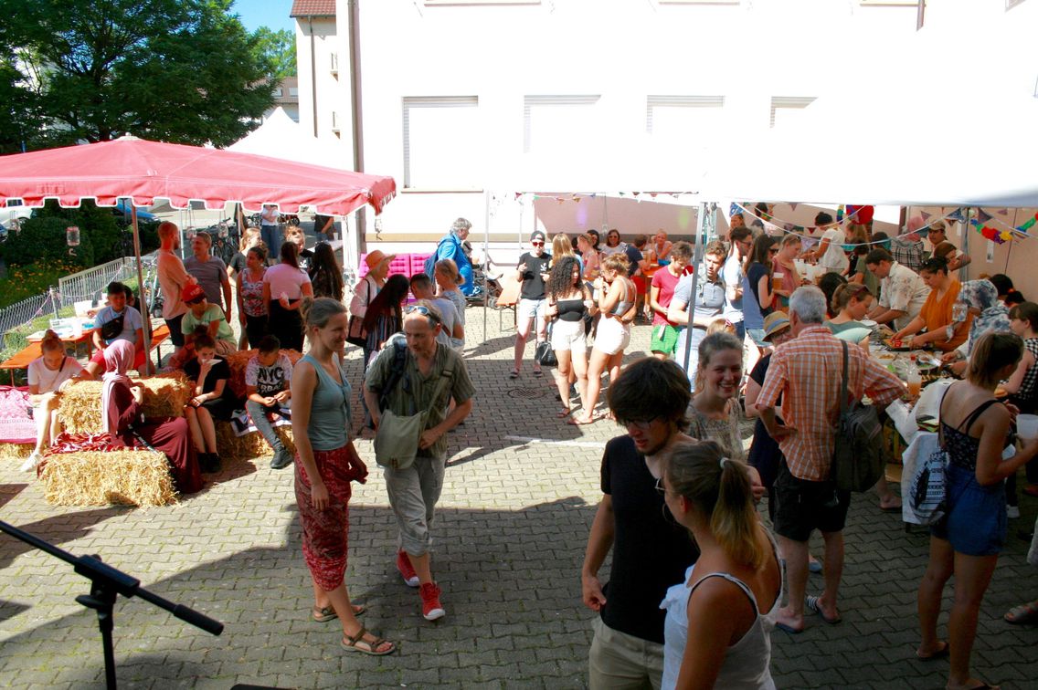 Das Haus des Engagements in Freiburg von außen. Im Hof tummeln sich viele junge und alte Leute bei einem Fest.